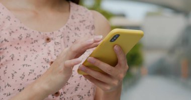 Kadın sokakta cep telefonu kullanıyor.