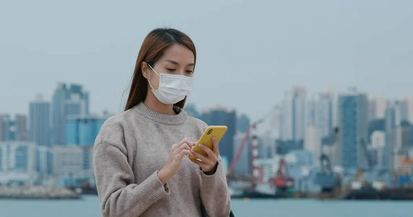 Woman wears face mask and uses mobile phone
