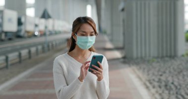 Woman wear medical mask and use of mobile phone at outdoor clipart