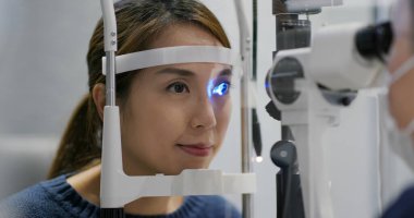 Klinikte kadın gözlerini kontrol ediyor.