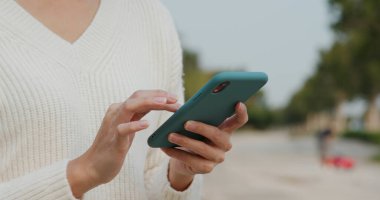 Kadın sokakta cep telefonu kullanıyor.