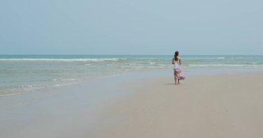 Kumsalda yürüyen bir kadın.