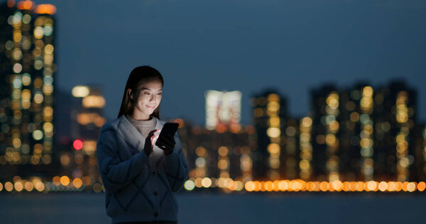 Woman look at cellphone in city at night