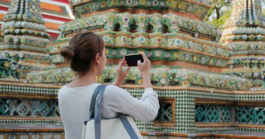 Tayland tapınağında cep telefonuyla fotoğraf çeken bir kadın.
