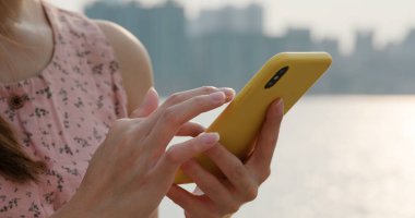 Kadın sokakta cep telefonu kullanıyor.