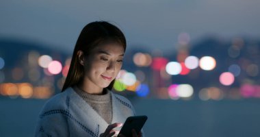 Kadın geceleri cep telefonuna bakar.