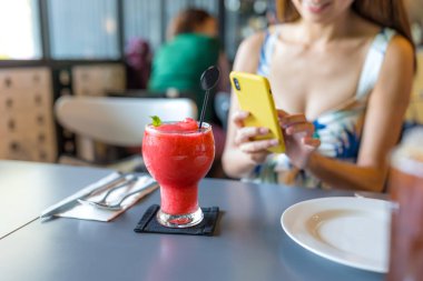 Kadın restoranda içkinin fotoğrafını çekiyor. 