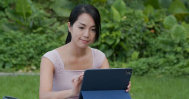 Kadın parkta tablet bilgisayarda çalışıyor.