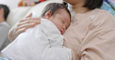 Anne evde bebeğine dokunuyor.