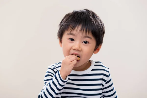 子供の男の子は白い背景にクッキーを食べる — ストック写真