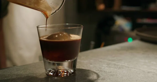 Pouring black coffee into tonic water in coffee shop