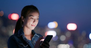 Gece vakti Hong Kong 'da bir kadın cep telefonu kullanıyor.