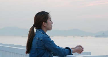 Kadınlar mavi kot pantolon giyer ve denize bakarlar.