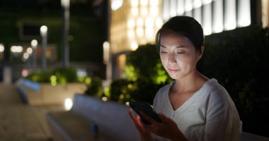 Gece vakti Hong Kong 'da bir kadın cep telefonu kullanıyor.