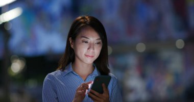 Kadın geceleri cep telefonuyla çalışıyor.