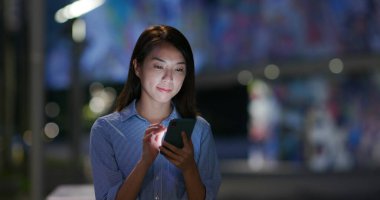 Kadın geceleri cep telefonuyla çalışıyor.