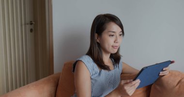 Kadın evde tablet bilgisayarda çalışıyor.