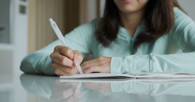 Kadın evdeki deftere yazıyor.