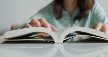 Kadın evde kitap okuyor.