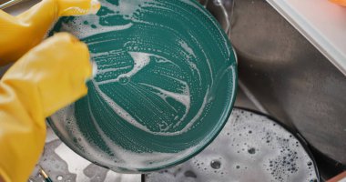 Kadın mutfakta bulaşık yıkıyor.