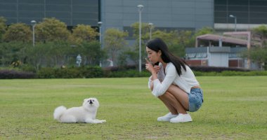 Kadın köpeğini eğitiyor.