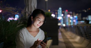 Kadın geceleri cep telefonunu kontrol ediyor.