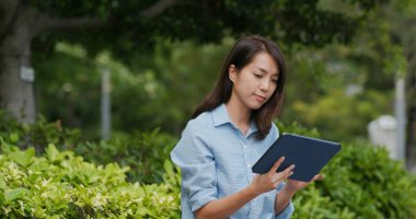 Kadın parkta tablet bilgisayarda çalışıyor.