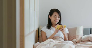 Kadın yatağında cep telefonu kullanıyor