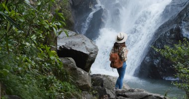 Kadın yürüyüşe çıkar ve ormandaki şelaleye gider.
