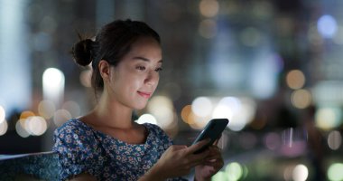 Geceleri kadın cep telefonu kullanıyor.