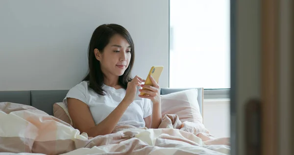 Woman read on cellphone on bed