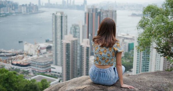 Woman sit at the top of the hill and enjoy the city view