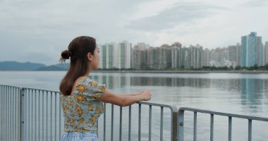 Kadın, deniz kenarındaki şehre bak.