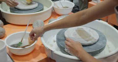 Kadın çömlekçi çömlek çarkında demlik yapıyor. 