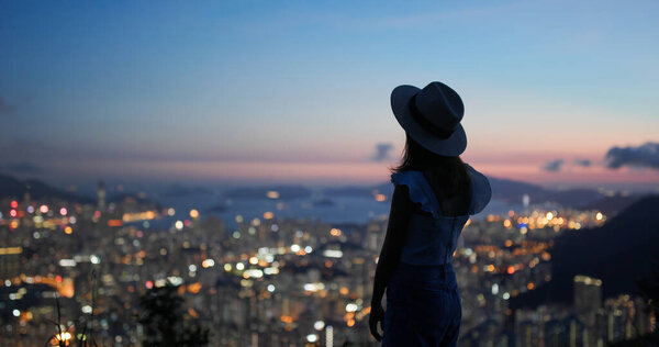 Woman tourist with straw hat and look at the city view at sunset time