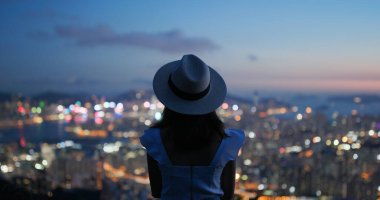 Kadın gün batımındaki güzel şehir manzarasına bak.