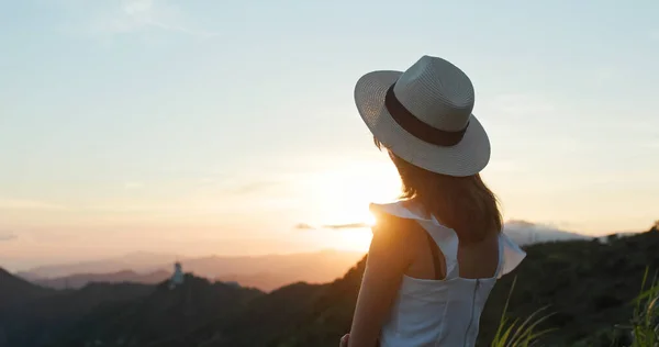 Travel woman wear straw hat and look at the mountain view in sunset time