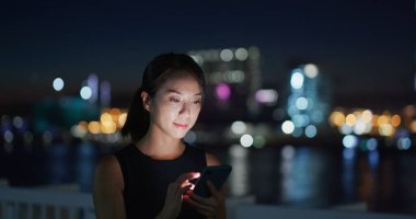 İş kadını geceleri şehirde akıllı telefon kullanıyor.