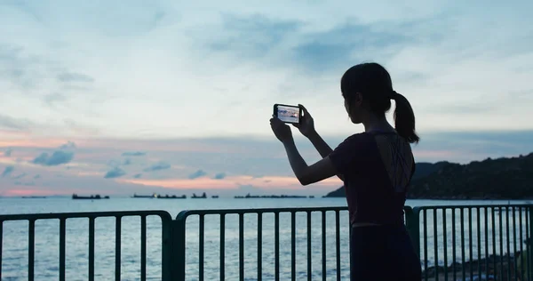Kobieta Korzystająca Mobilnego Zdjęcia Zrobić Zdjęcie Zachodzie Słońca Nad Morzem — Zdjęcie stockowe