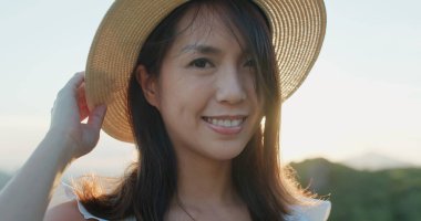 Kadınlar hasır şapka takar ve dağda kameraya gülümserler.