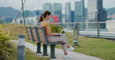 Kadın parkta dizüstü bilgisayarda çalışıyor.