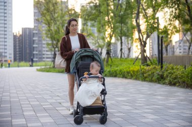 Mother pushing baby stroller walking outside together