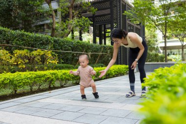Mother let baby walk alone at outdoor