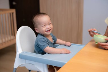 Küçük oğlan kaşıkla bebek mamasıyla besleniyor.