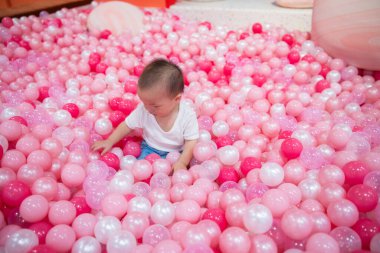 Little baby having fun in pink ball