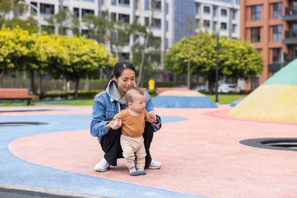 Mom teaching baby walking in sunny park
