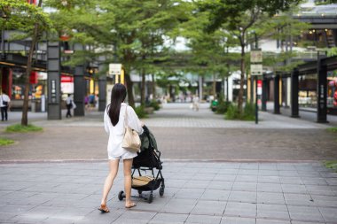 Mother pushing stroller while walking on city street