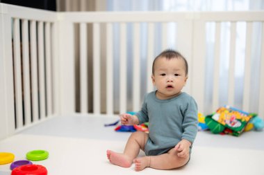 Infant having playful time inside home playpen
