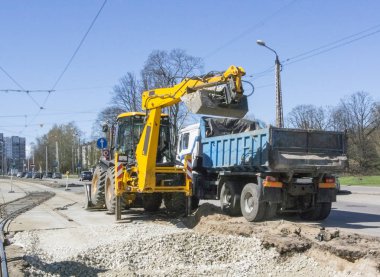 İş yerindeki erkekler. Kazıcı kamyon gövdesine ezilmiş taş yüklüyor.