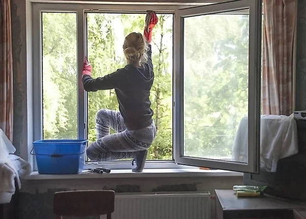 波罗的海 拉脱维亚 2017年7月19日 女孩在橡胶手套洗涤窗口 坐在窗台在房间里在夏天 — 图库照片